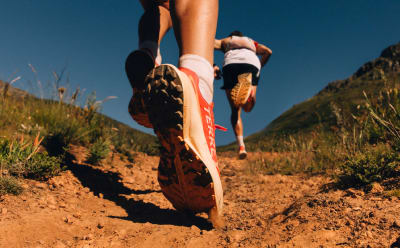 A close up image of two runners wearing Agravic shoes, ascending a trail.