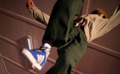 A kid is seen jumping over the camera, wearing adidas Originals.