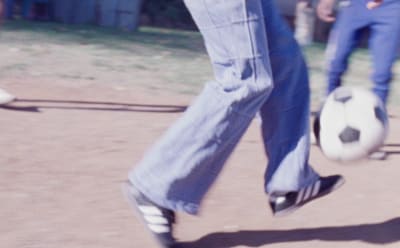 A person is photographed playing with a football, wearing adidas Originals.