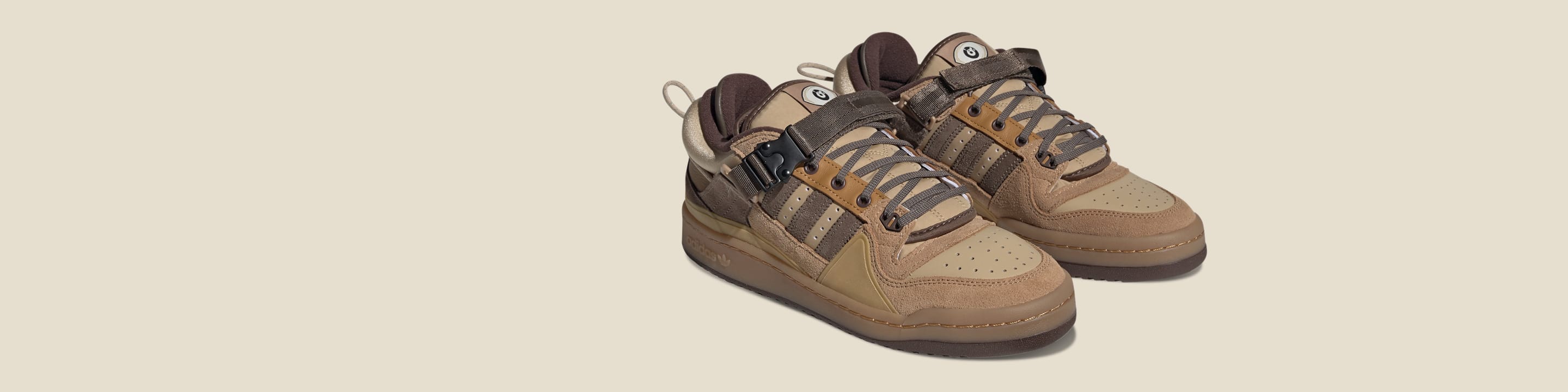 A pair of the brown Bad Bunny Forum sneakers sitting next to two sets of blue and green laces and a set of additional snap-on tongues.