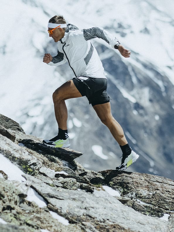 Athlete Dima wearing the Agravic Ultra running up rocky mountain trails