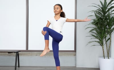 A girl is holding a yoga pose wearing a yoga top and leggings from the Make Space yoga collection.