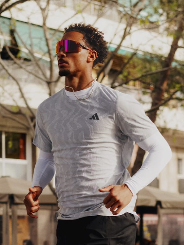 Image of a man running outdoors wearing adidas apparel.