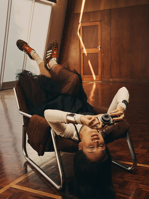 A person is lying on a chair, holding a video game controller, with a wooden background.