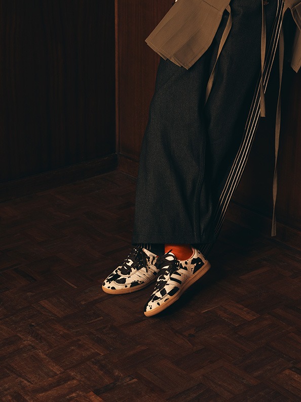 A pair of patterned shoes sits on a wooden floor in a dimly lit room, with a dark background suggesting a somber or mysterious atmosphere.