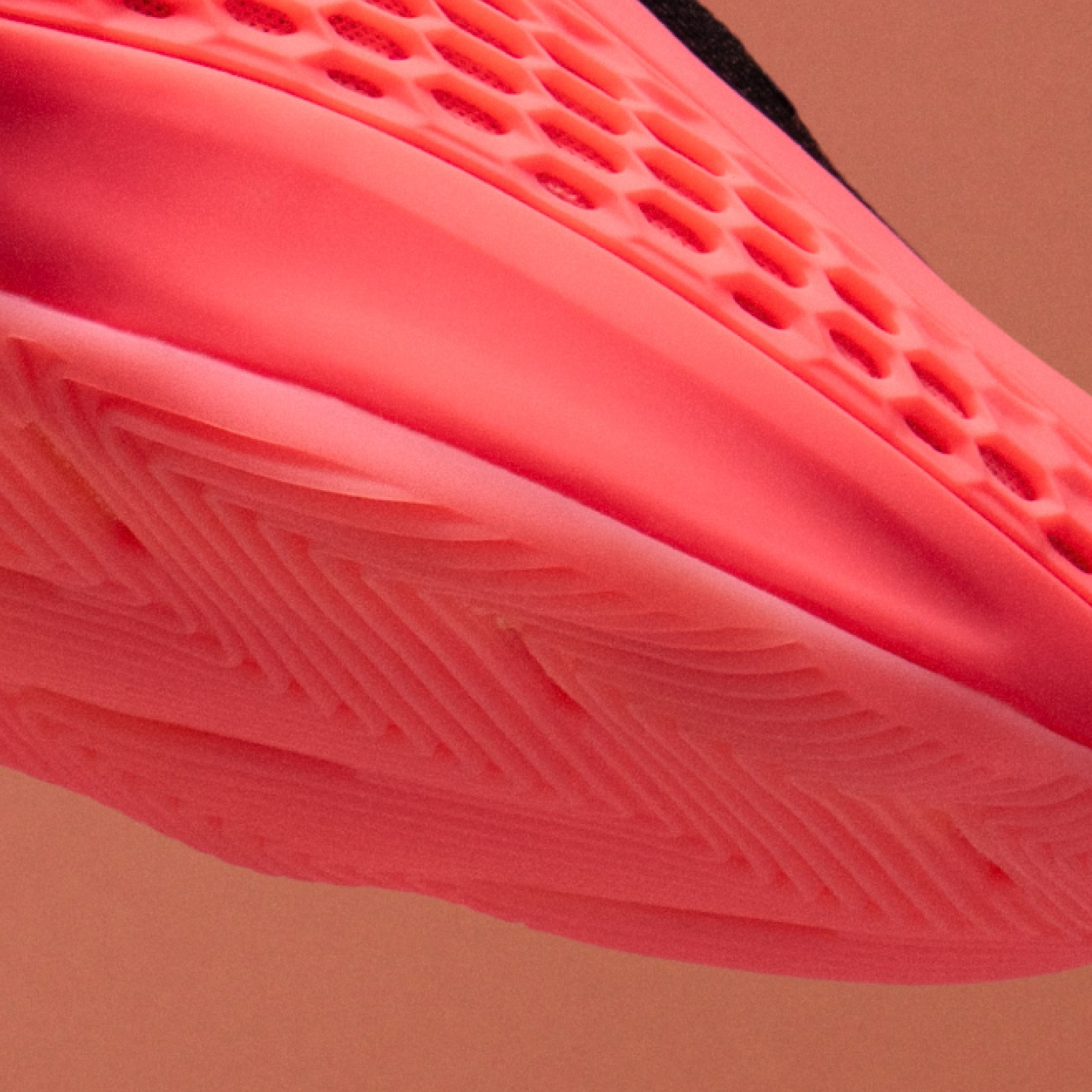 The image shows a close-up view of a textured, pink surface with a honeycomb-like pattern, set against a dark background.