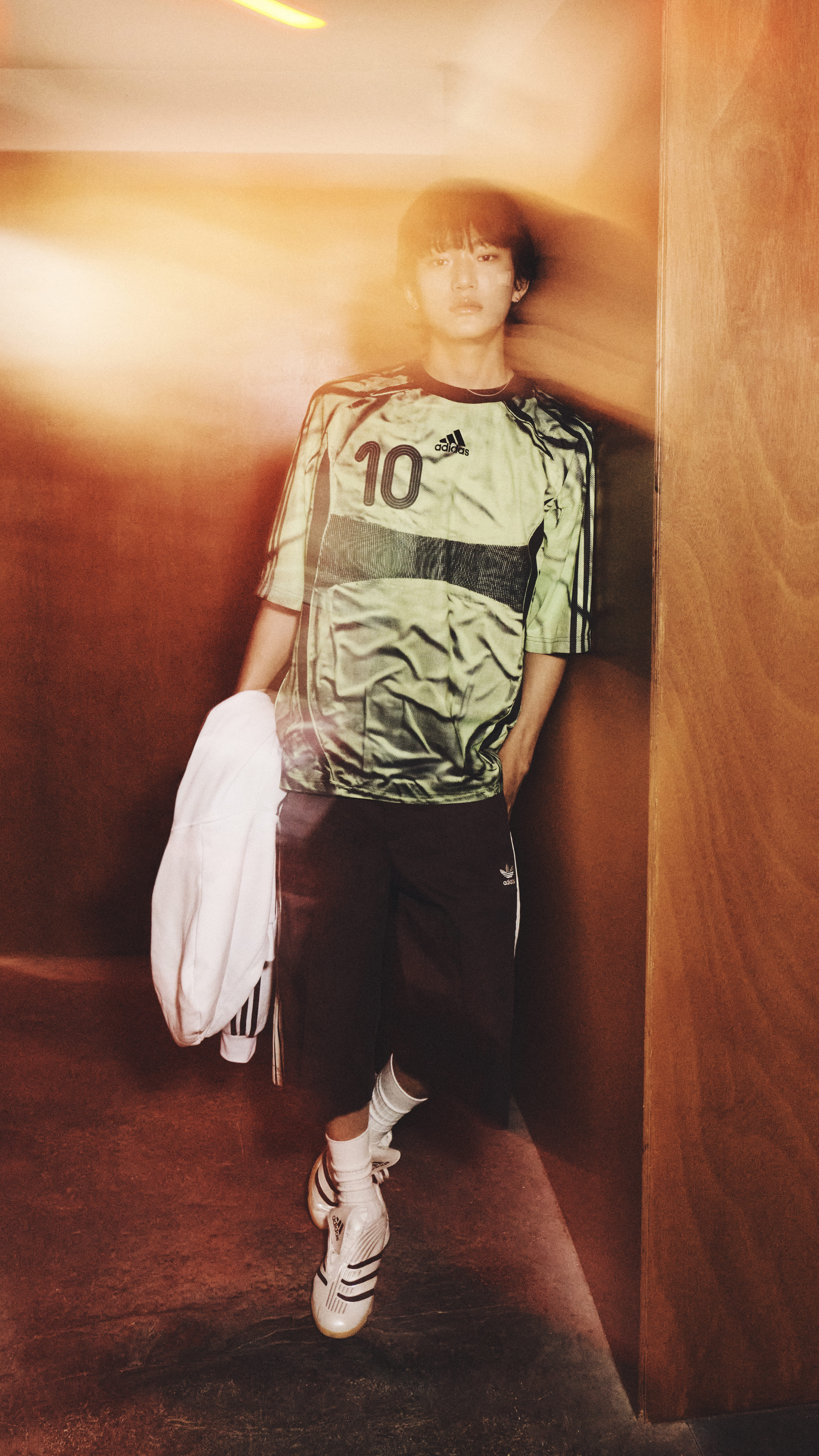 A person wearing a jersey with the number 10 stands in a dimly lit room, their face partially obscured by the blurred motion.