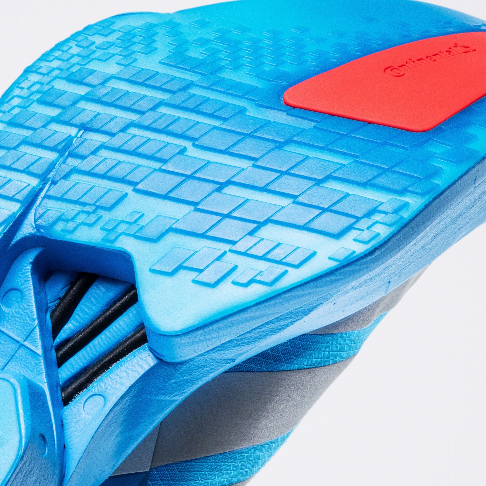 The image shows a blue and red sports shoe with a textured sole and a distinctive pattern on the upper part.