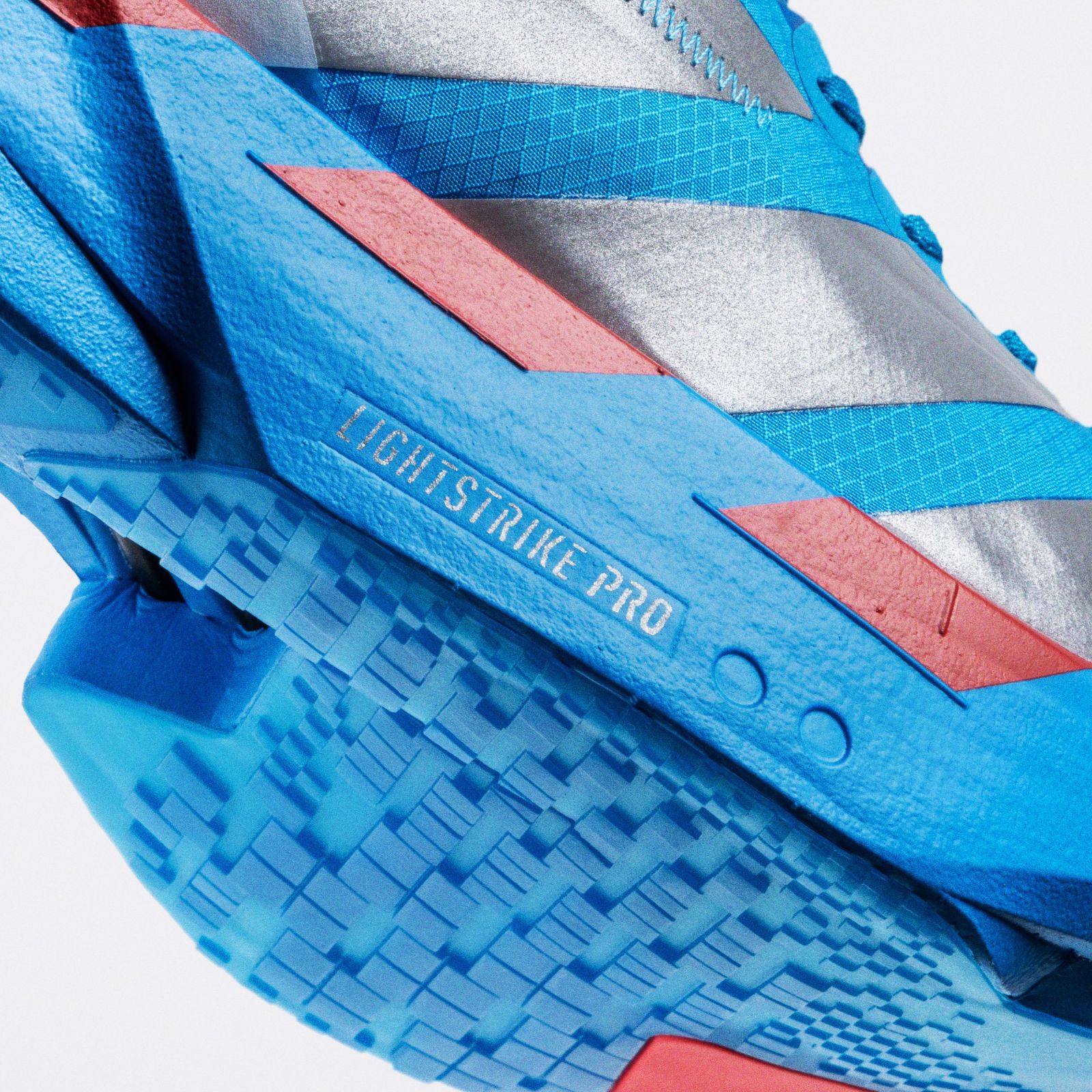 The image shows a close-up view of a blue and pink athletic shoe with a textured sole and the text "Lightweight Pro" visible on the side.