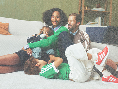 A family of four, including a man, woman, and two children, are sitting together on a couch in a cozy living room setting.