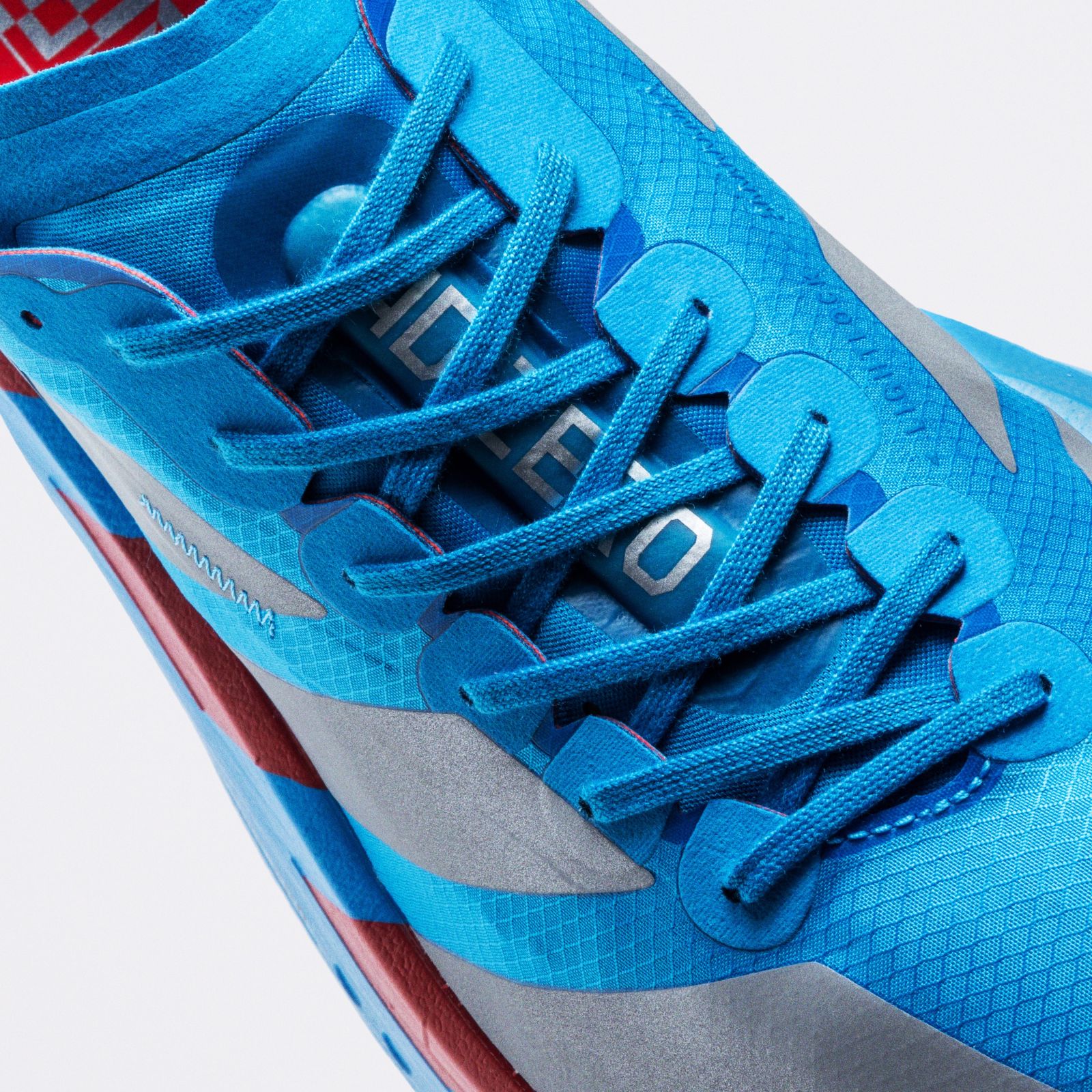 A close-up view of a pair of bright blue athletic shoes with intricate lacing and a textured sole, set against a plain white background.