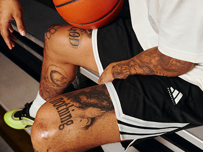 The image shows a person's arm with several tattoos, including a basketball and the word "Winning" written on the skin. The person is also holding a basketball.