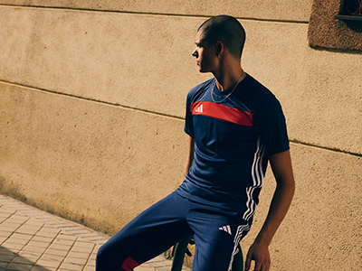 A person wearing a navy blue and red athletic jersey stands in front of a beige concrete wall.