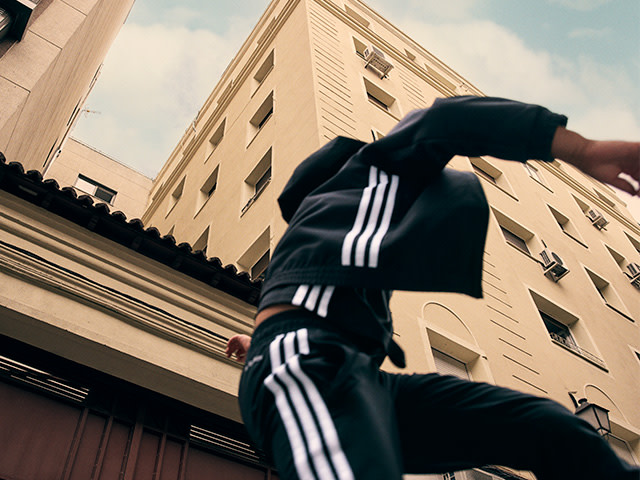 A person wearing a black jacket with white stripes stands in the foreground, with a tall, ornate building in the background.