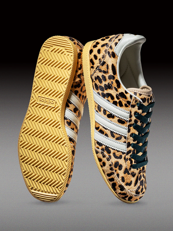 A pair of leopard-print sneakers with a distinctive yellow zigzag pattern on the soles, set against a dark background.