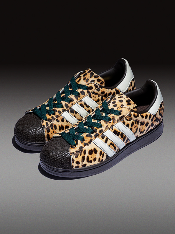 A pair of leopard-print sneakers with black and white accents, set against a dark background.