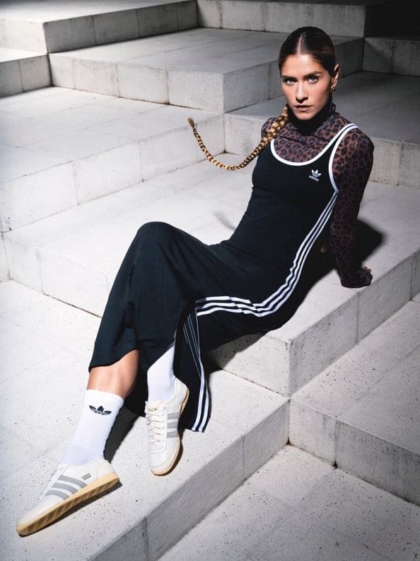 A person wearing a black and white striped outfit is sitting on a set of concrete steps, with a serious expression on their face.
