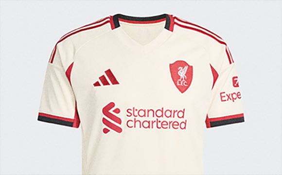 A white and red soccer jersey with the Standard Chartered logo and the Expedia logo on a plain white background.