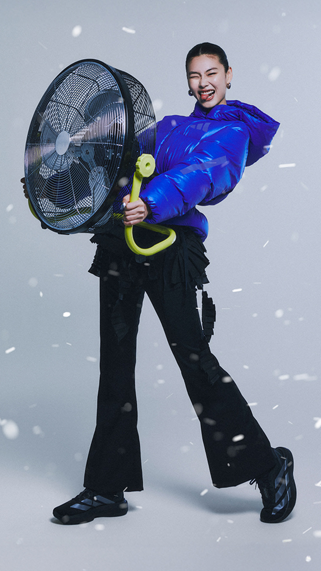 A person in a bright blue costume holding a large fan, standing against a snowy background.