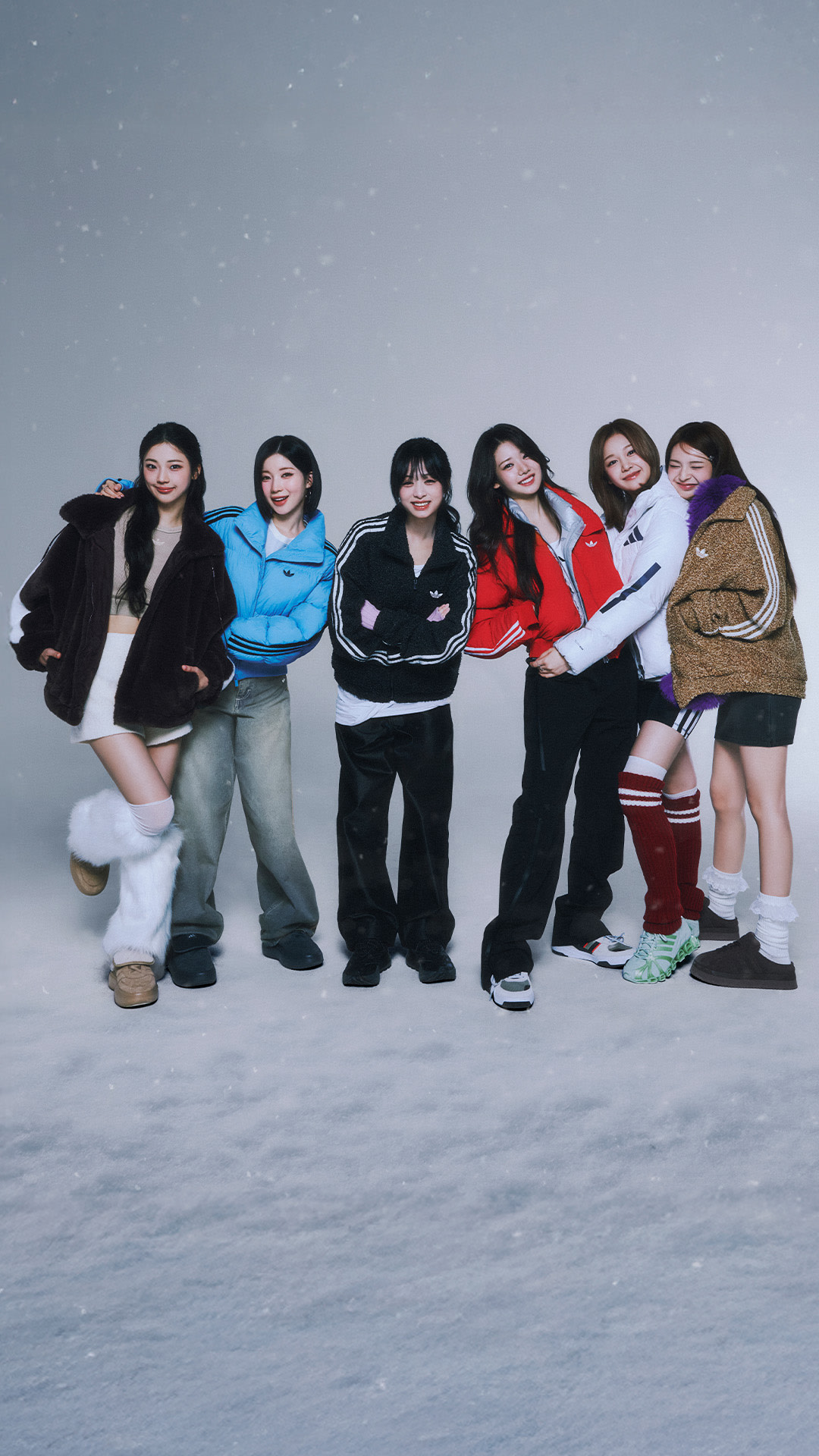 A group of six young women in casual winter attire standing together in a snowy outdoor setting with a clear night sky in the background.