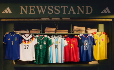 A newsstand display showcasing a variety of colorful soccer jerseys from different national teams, set against a dark background with the word "NEWSSTAND" prominently displayed.