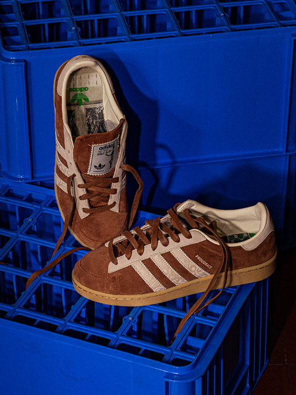 A pair of brown and white sneakers sits in a blue plastic crate against a vibrant blue background.
