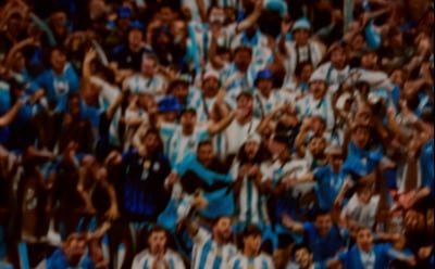 A blurred and abstract image with a mix of warm and cool tones, featuring a chaotic and dynamic pattern of overlapping shapes and textures.