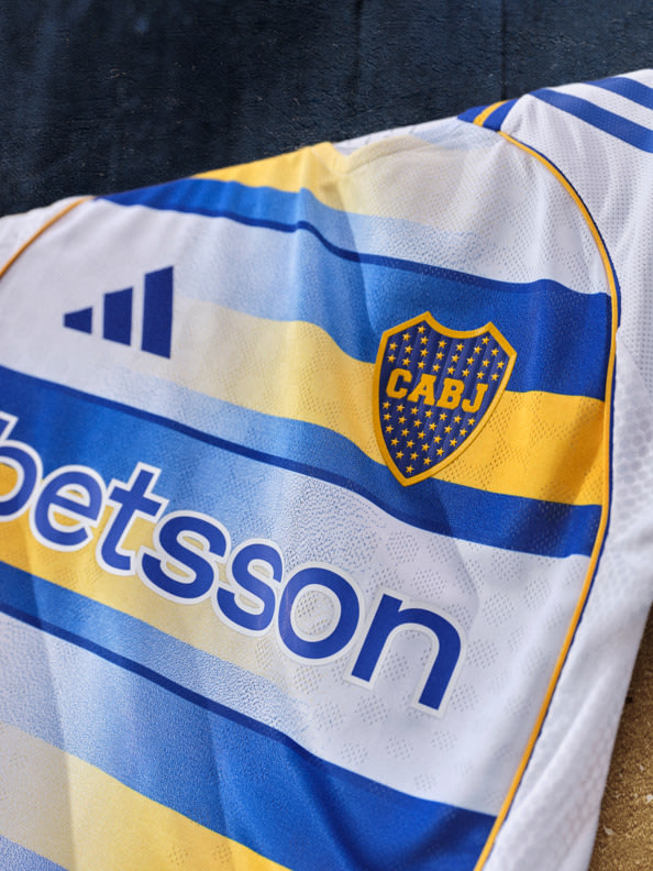 The image shows a close-up view of a sports jersey or uniform featuring the Boca Juniors logo and the Betsson sponsor branding, set against a dark background.