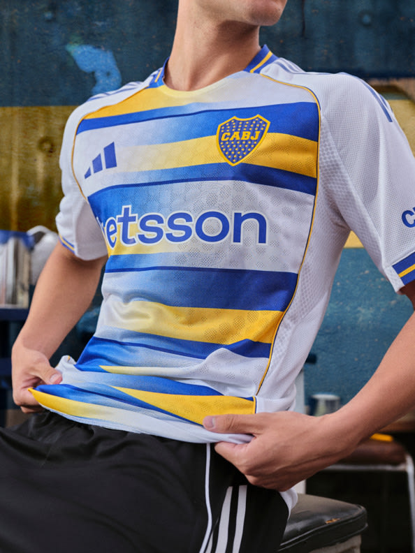 The image shows a person wearing a white, blue, and yellow striped jersey with the text "Etsson" printed on it, standing in what appears to be a sports facility or stadium.