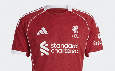 A red and white soccer jersey with the "Standard Chartered" logo and the Liverpool Football Club crest prominently displayed.