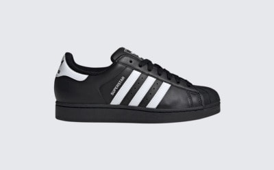 A black and white Adidas Superstar sneaker is shown against a plain light background.