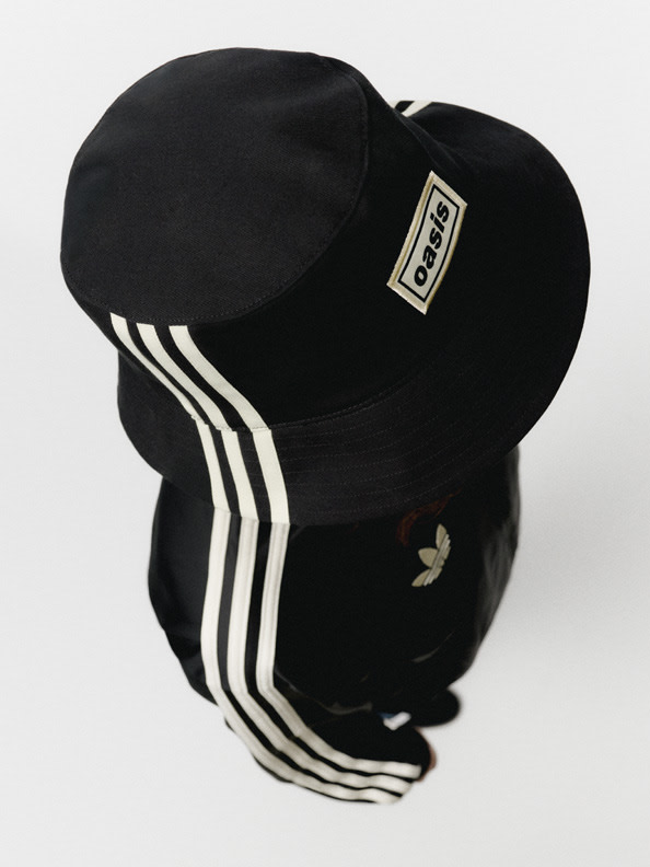 A black baseball cap with white stripes and an Adidas logo is the focal point of the image, set against a plain white background.