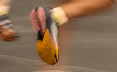 A blurred image of a person's feet wearing colorful sneakers, with the background appearing to be a smooth, gray surface.