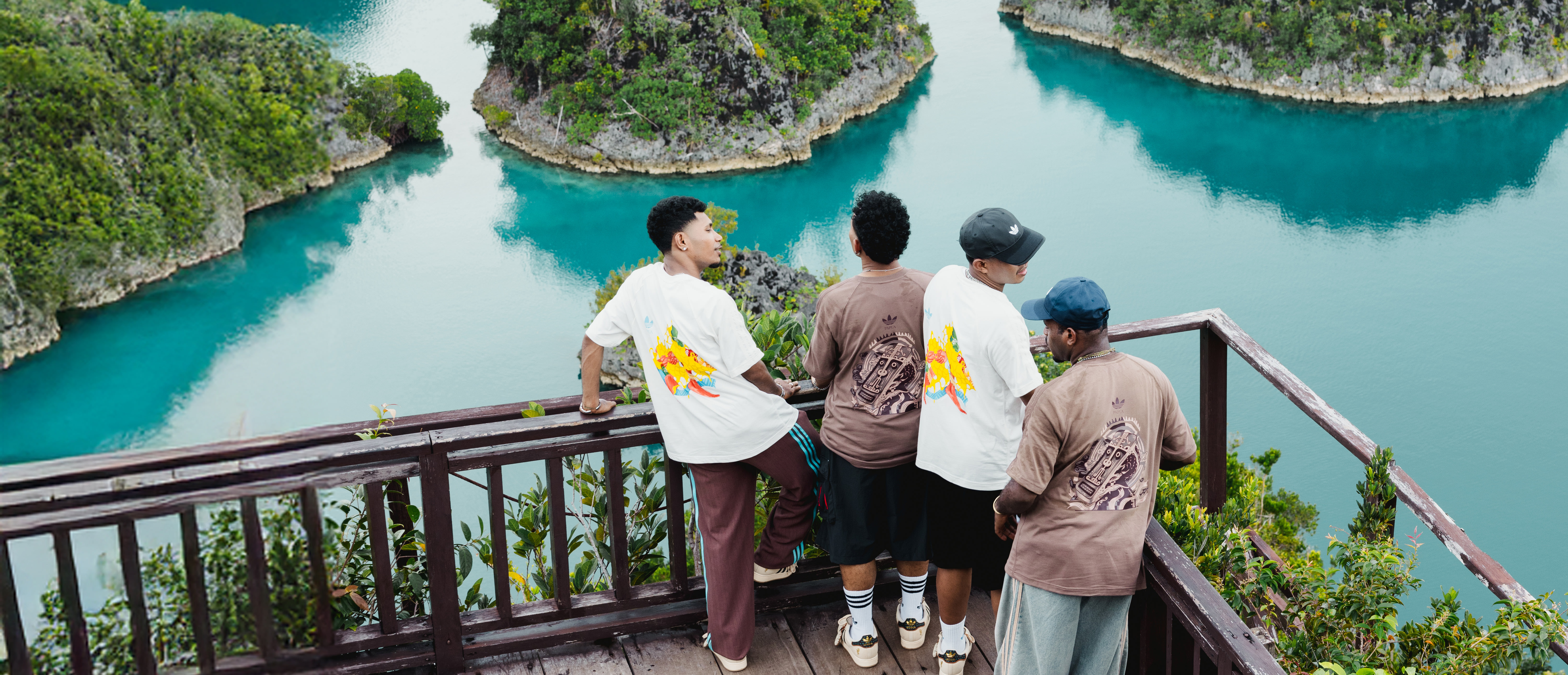 A group of people standing on a wooden platform overlooking a stunning turquoise lagoon surrounded by lush, towering cliffs.