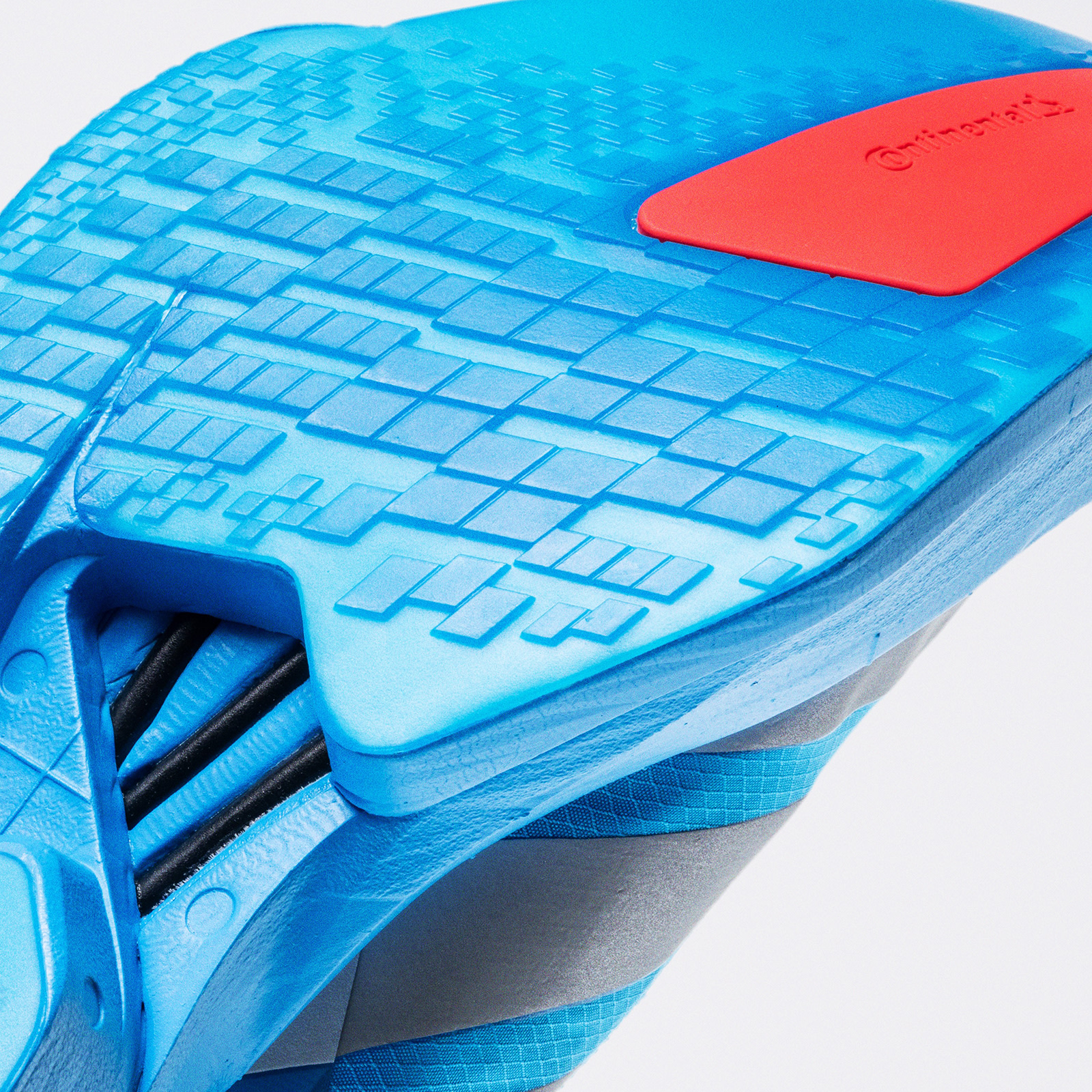 The image shows a blue and red sports shoe with a textured sole and a distinctive pattern on the upper part.