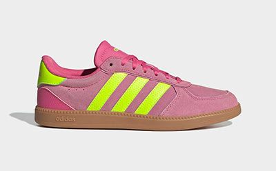 A pair of vibrant pink and neon green Adidas sneakers with a gum sole, set against a plain white background.