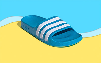 A blue and white striped slide sandal rests on a vibrant yellow and blue background.