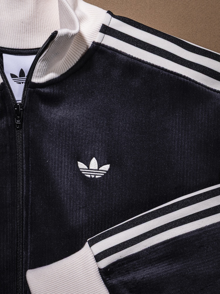 A black and white Adidas tracksuit jacket with the iconic Adidas logo prominently displayed on the front.