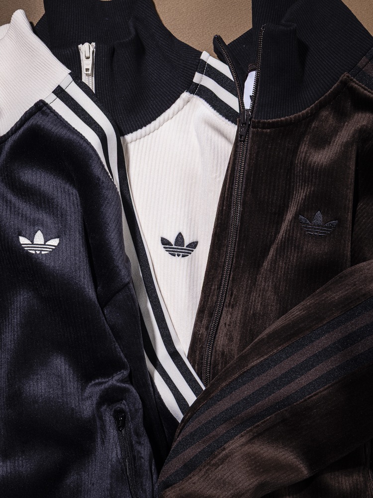 The image shows several Adidas sportswear items, including a black jacket with white stripes, a white shirt, and a brown jacket, all featuring the iconic Adidas logo.