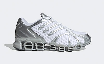 A futuristic-looking white and silver athletic shoe with a distinctive sole design and perforated upper, set against a plain background.
