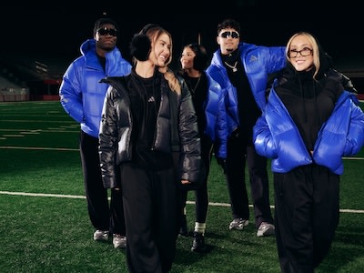 Un grupo de personas con chaquetas azules y negras de pie en un campo deportivo por la noche.