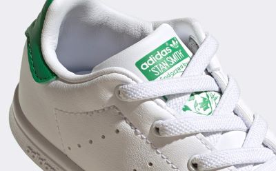 Nahaufnahme eines weiß-grünen adidas Stan Smith Sneakers mit dem legendären adidas Trefoil Logo an der Seite.