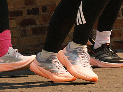 The image shows a pair of colorful sneakers with a brick wall in the background.