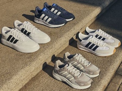 Several pairs of Adidas sneakers are arranged on stone steps in the foreground, with a blurred outdoor background.