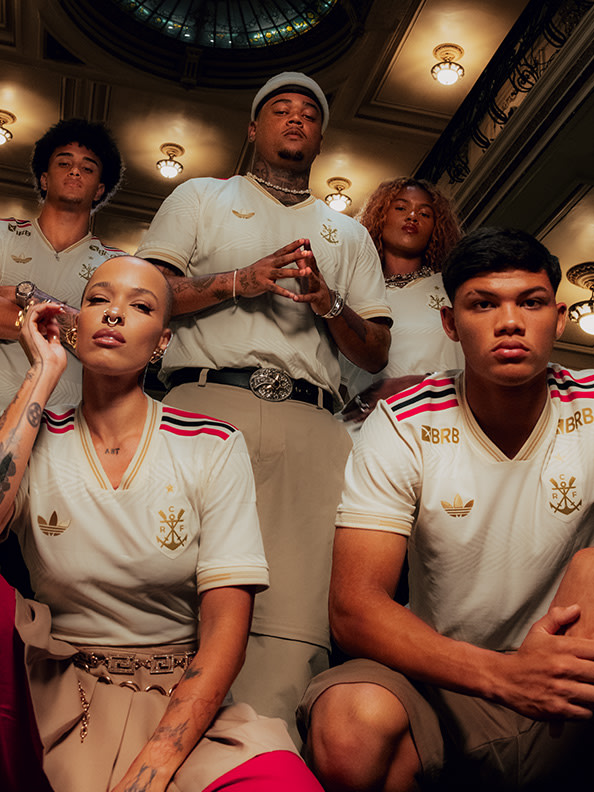 The image depicts a group of individuals wearing matching white and red uniforms, posing together in what appears to be an indoor setting with a domed ceiling and decorative lighting fixtures.