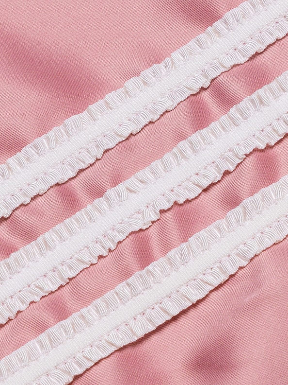 The image shows a close-up view of a pink fabric with delicate white ruffled trim running diagonally across the frame, creating a soft and textured visual effect.