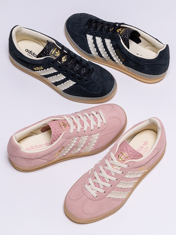 The image shows a pair of black and white Adidas sneakers and a pair of pink and white Adidas sneakers on a light background.
