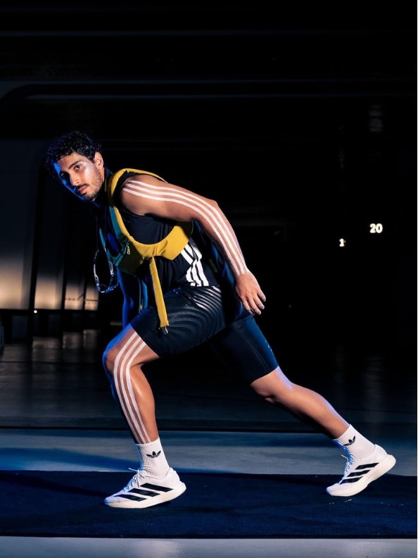 A person in athletic clothing is captured in a dynamic pose, with colorful lighting illuminating the scene against a dark background.