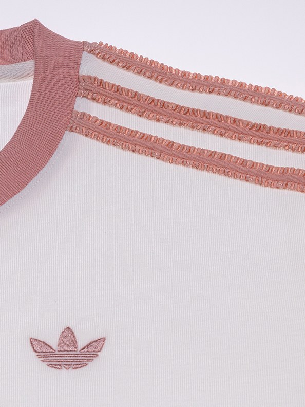 The image shows a close-up view of a white t-shirt with a pink Adidas logo and pink ruffled trim along the neckline and sleeves.