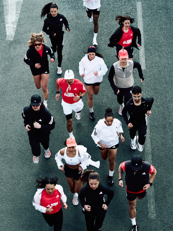 A group of people, mostly dressed in athletic attire, are walking or running on a paved surface surrounded by a gray, concrete-like background.